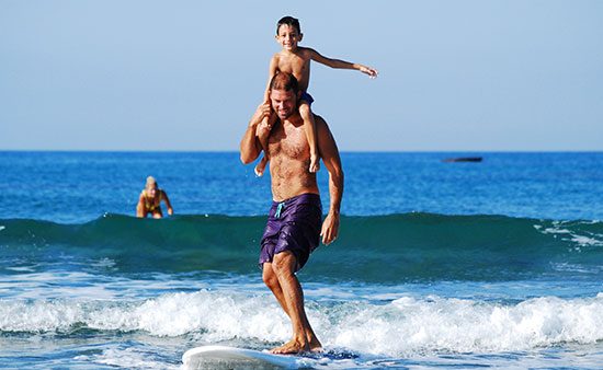 life management father surfing with kid on shoulders